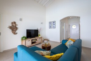 A living room with a blue sofa, a TV on a wooden stand, and a decorative wall piece.
