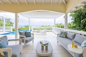 A covered outdoor seating area with a pool in the background. - Sea-view Caribbean villa with private pool (Sint Willibrordus)