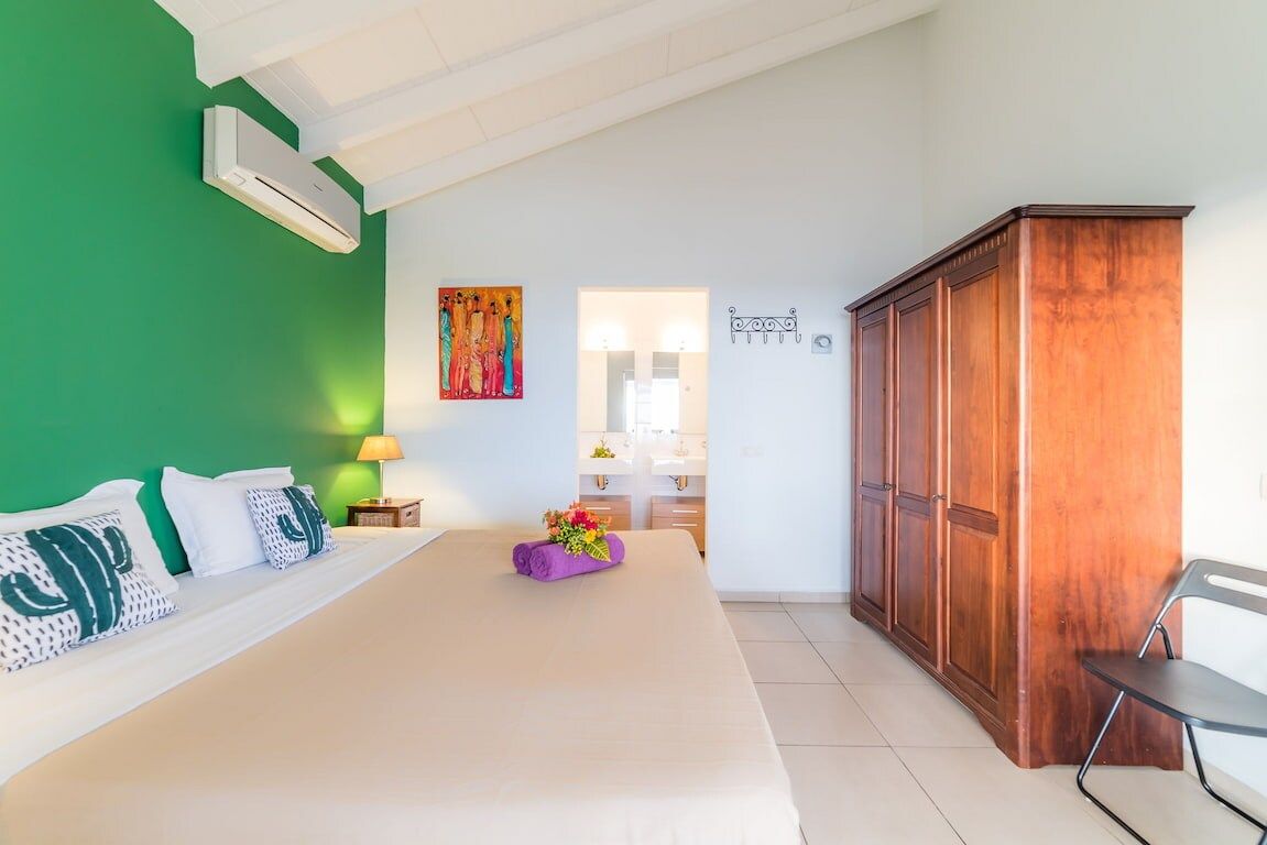 Ein Hotelzimmer mit einem Bett, einem Holzschrank, einem Badezimmer mit Spiegel und einer grünen Wand.