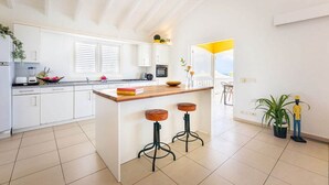 Eine moderne Küche mit weißen Schränken, einer Holzinsel mit Sitzgelegenheiten und Blick ins Freie.