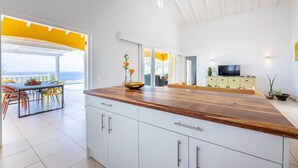 Eine moderne Küche mit einer Holz Arbeitsplatte, weißen Schränken und Blick auf das Meer.