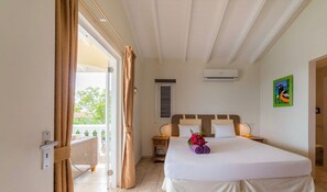 Habitación de hotel con una cama, una mesita de noche, un equipo de aire acondicionado, una ventana con cortinas y un cuadro en la pared.