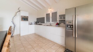 A modern kitchen with white cabinetry, a stainless steel refrigerator, and a built-in oven. - Elegant sea-view villa with private pool - Coral Estate (Sint Willibrordus)