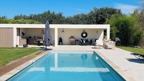 A rectangular pool with a tiled deck, surrounded by a covered patio area with outdoor furniture. - Provencal Escape: Villa with Pool and Pool House in the Heart of the Luberon (La Tour-d'Aigues)