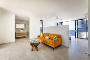 A modern living room with a sofa, a glass coffee table, and a view of the sea through large windows. - Luxury sea view villa with private pool (Sint Willibrordus)