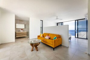 A modern living room with a sofa, a glass coffee table, and a view of the sea through large windows. - Luxury sea view villa with private pool - Coral Estate (Sint Willibrordus)