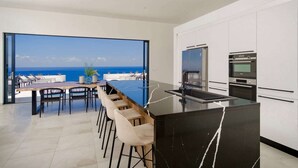 Una cocina moderna con una isla grande, un comedor con vista al océano, y horno y microondas integrados.