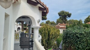 Un bâtiment blanc avec un toit en tuiles et un balcon agrémenté de mobilier d’extérieur.
