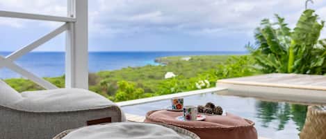 A poolside area with a view of the ocean and lush greenery.