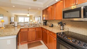 Una cocina moderna con encimeras de granito, armarios de madera, microondas empotrado y horno de acero inoxidable.