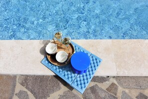 A poolside setting with a table holding glasses, a cup, and a woven mat. - Villa With Private Pool and Garden Retreat (Groznjan)