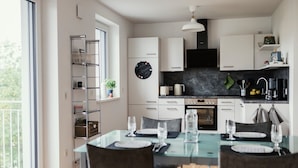 A modern kitchen with white cabinets, a black countertop, and a dining area with a glass table and chairs.