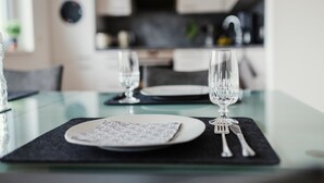 A dining table with a glass top, a plate, a napkin, and cutlery.