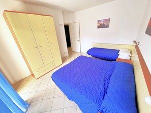 Una habitación con dos camas, un armario y una puerta que da a otra estancia.