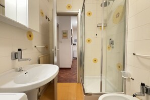 Une salle de bain équipée d’un lavabo, d’un miroir, d’une douche et de toilettes.