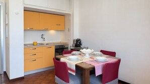 Eine kompakte Küche mit Esstisch, gedeckt für vier Personen, mit kariertem Tischläufer und roten Stühlen.