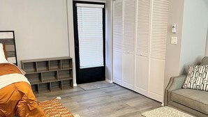 A modern bedroom with a bed, a sofa, a patterned ottoman, a built-in bench, and a wardrobe. - Cozy 1-bedroom studio in superb Ocala with AC comfort (Ocala)