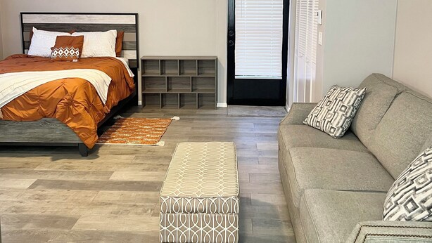 A bedroom with a bed, a sofa, a ceiling fan, and a door with blinds. - Cozy 1-bedroom studio in superb Ocala with AC comfort (Ocala)