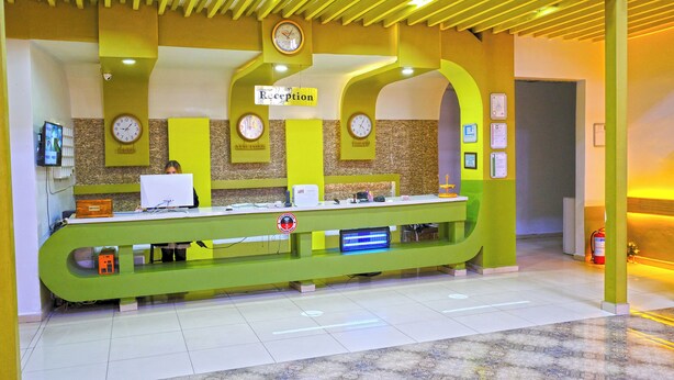 A reception desk with a clock, a sign reading 'Reception,' and a fire extinguisher. - Divanyolu Otel (Şanlıurfa)