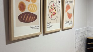 Drei gerahmte Illustrationen von Speisen an einer Wand.