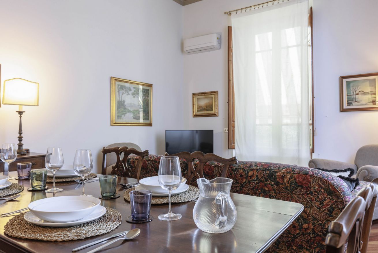 A dining area with a table set for four, a television, and a sofa.