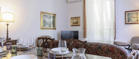 A dining area with a table set for four, a television, and a sofa.