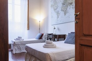 A hotel room with two beds, a desk, a lamp, and a world map on the wall. - Spartaco Prestigious Apartment (Firenze)
