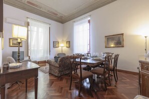 A dining area with a wooden table, chairs, and a sofa. There are framed pictures on the walls and a lamp on the table. - Spartaco Prestigious Apartment (Firenze)