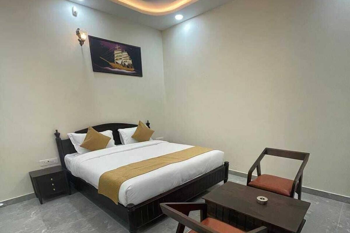 A hotel room with a bed, bedside table, and a small table with chairs.