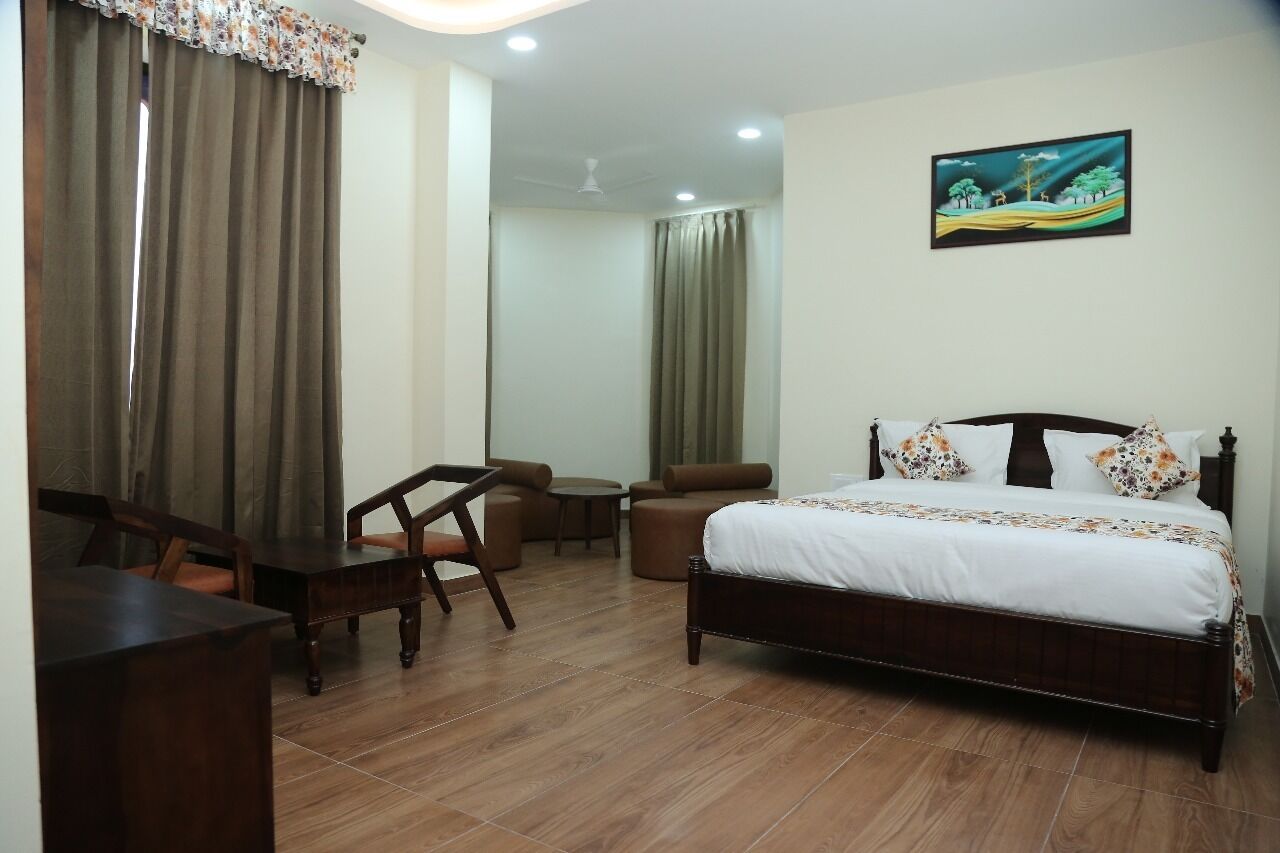 A hotel room with a bed, a desk, a chair, a small table, and a sofa.