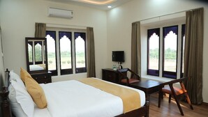Ein Hotelzimmer mit Bett, Schreibtisch, Stuhl, Fernseher und großen Fenstern mit Vorhängen.