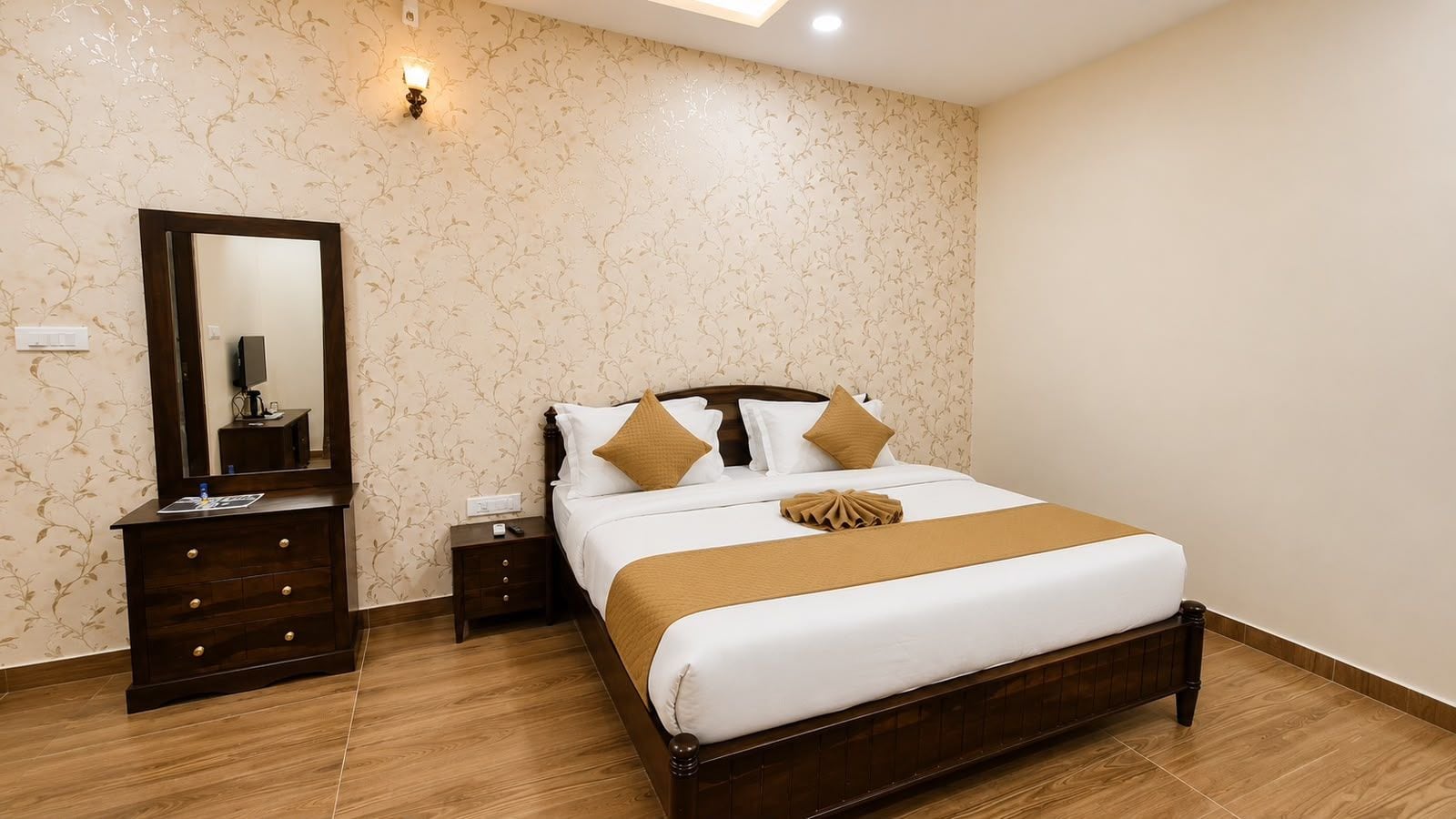 Una habitación de hotel con cama, cómoda, mesita de noche, espejo y lámpara de pared.
