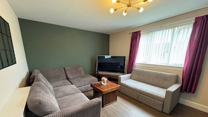 A living room with two sofas, a TV, and a wooden coffee table.