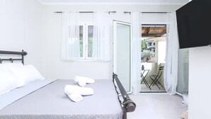 A bedroom with a bed, a window with sheer curtains, a door leading to a balcony, and a television on the wall. - Elite Villa Ena in Ano Korakiana (Corfu)