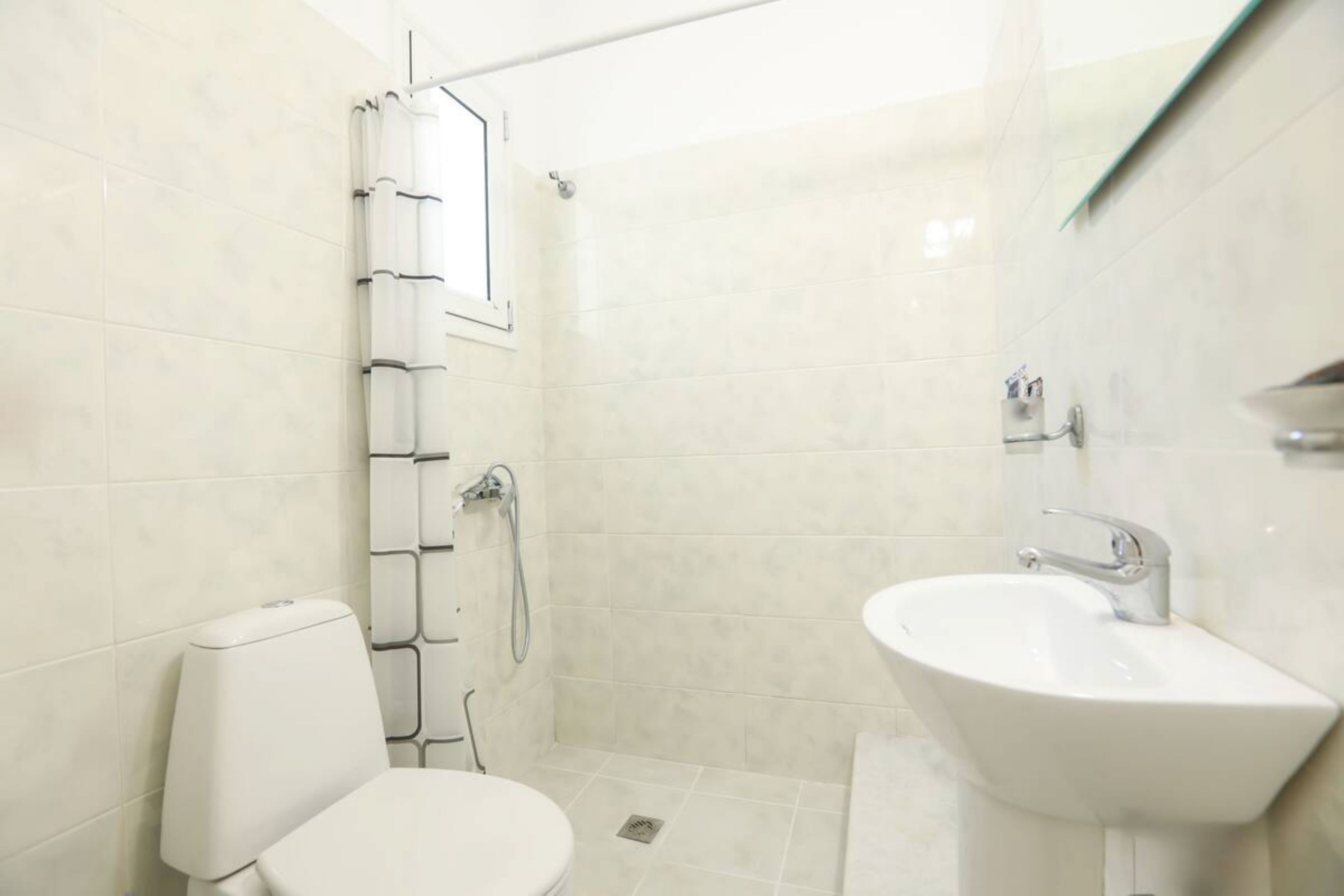 A bathroom with a toilet, a shower, and a sink.