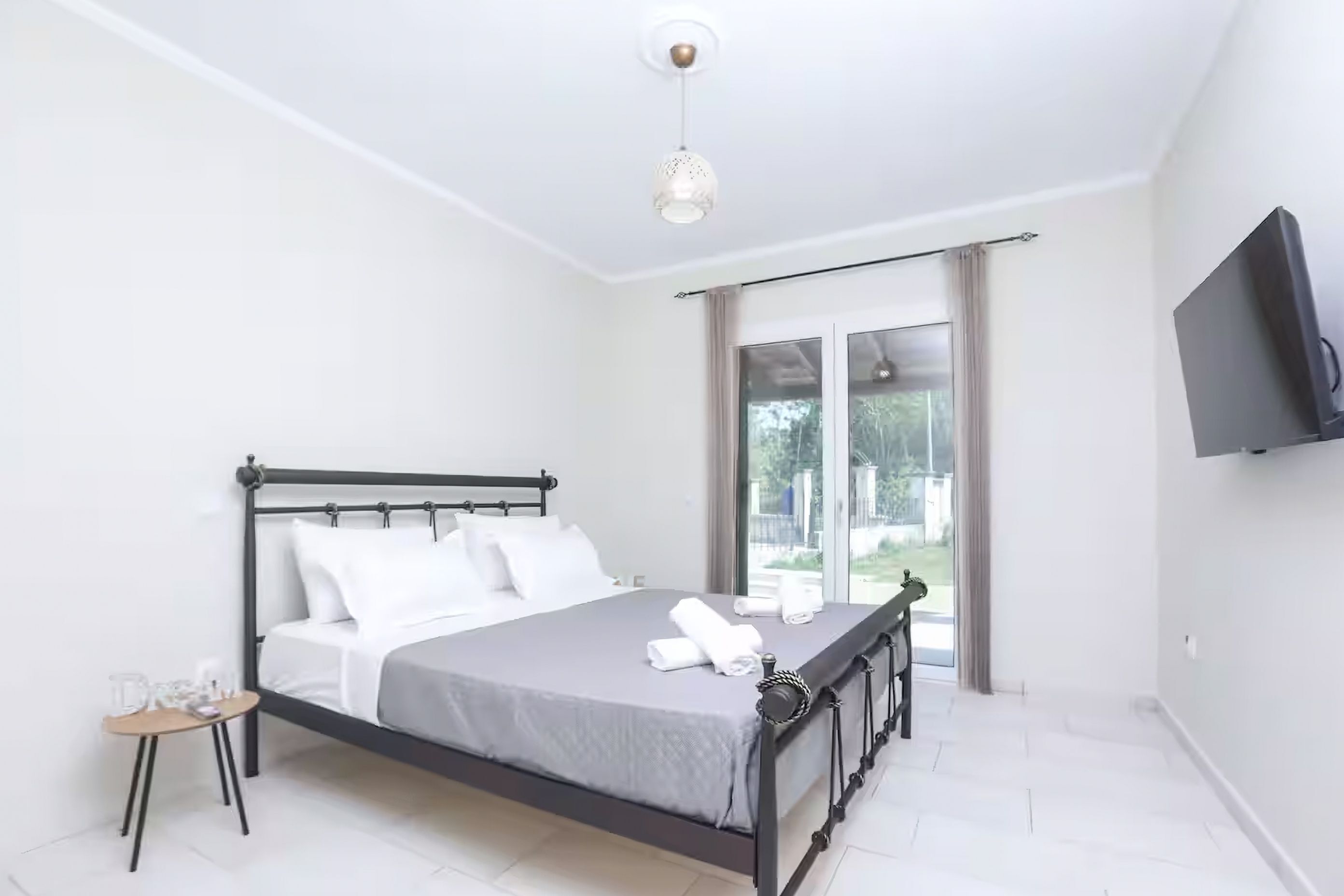 A modern bedroom with a bed, bedside table, and a TV mounted on the wall.