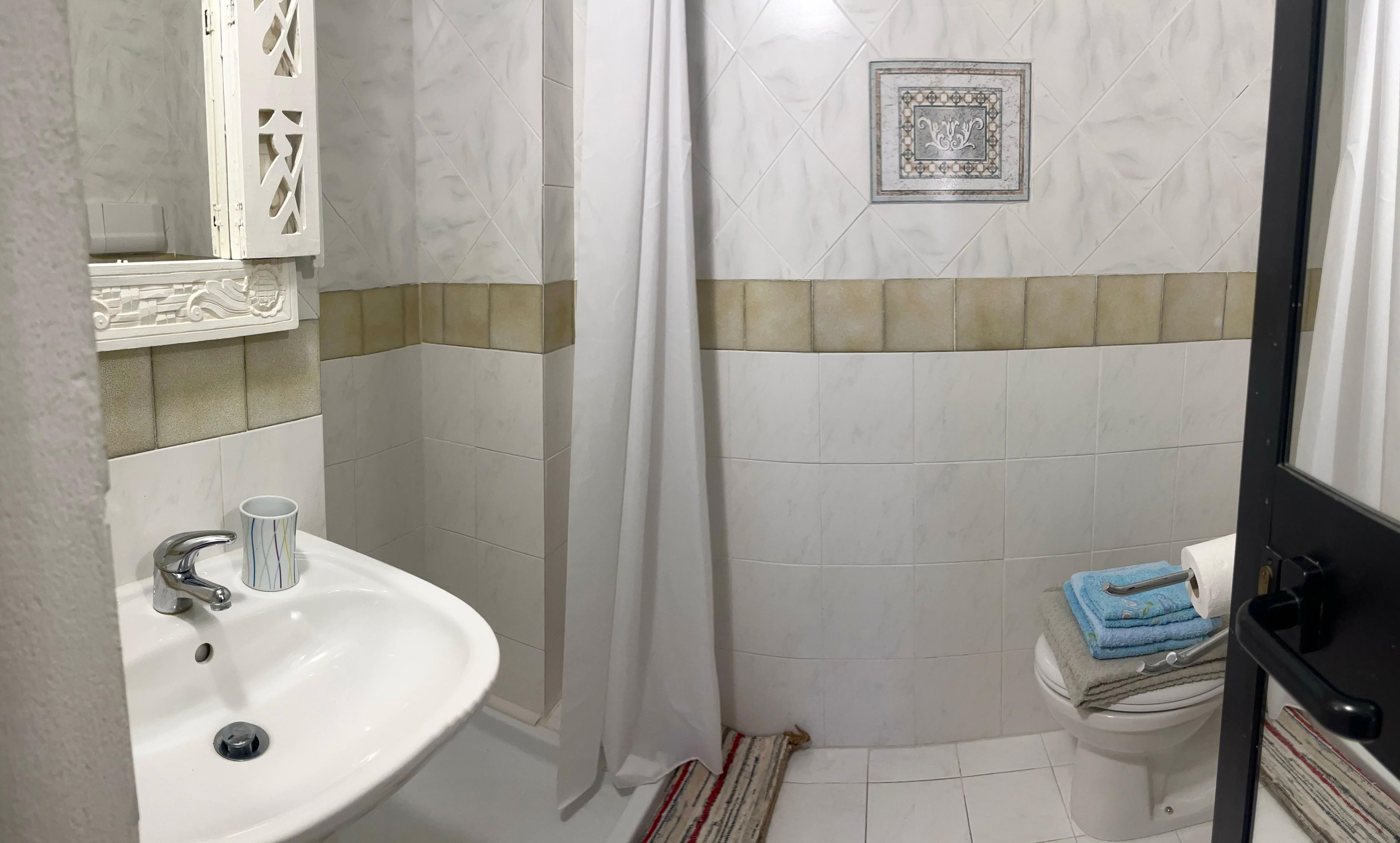 Un bagno con un lavandino bianco, un water e una tenda per la doccia.