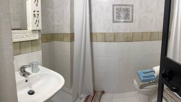 Un bagno con un lavandino bianco, un water e una tenda per la doccia.