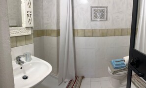 A bathroom with a white sink, a toilet, and a shower curtain.