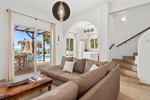 A modern living room with a sectional sofa, a wooden coffee table, and a glass door leading to a pool area. - Beach Front Villa Thaleia, Sea Views, 3 BDR, Private Pool, Furnished Terrace,. (Famagusta)