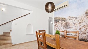 Zona pranzo con tavolo e sedie in legno, una scala e un affresco sulla parete.