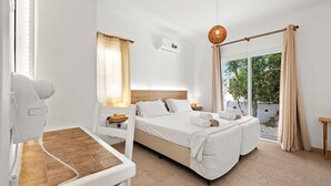 Una camera d'albergo con un letto, una poltrona massaggiante, una finestra con tende, un condizionatore e vista sull'esterno.