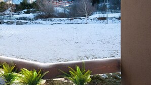A snowy landscape with a mountain in the background, a street lamp, and a few potted plants in the foreground. - Residenze Holiday Park by Halldis (Ponte di Legno)