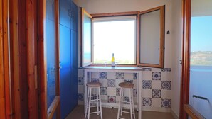 Eine Küche mit Fenster, zwei Hocker und blauen Schränken.