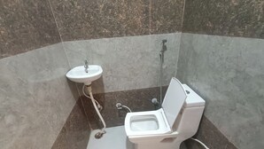 A bathroom with a toilet, sink, and shower. - Hotel Krishnam Palace (Vrindavan)