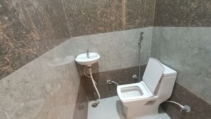 A bathroom with a toilet, sink, and shower. - Hotel Krishnam Palace (Vrindavan)