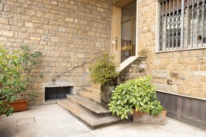 A stone building with a fireplace, steps leading up to a door, and potted plants. - Modern Apartment with Skyline Views (Firenze)