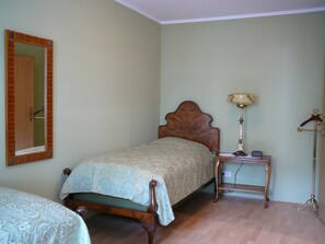 Un dormitorio con una cama, una mesita de noche con lámpara, un espejo y un armario.