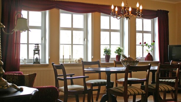 A dining area with a chandelier, wooden chairs, a table, and large windows with curtains. - Apartment 'Richard W, 90 sqm' in Weimar – up to 8 adults (Weimar)
