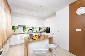 Une cuisine moderne avec des armoires blanches, un plan de travail en bois, un mixeur et un évier.